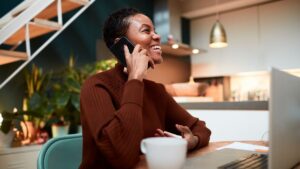 young black woman using business mobile phone at desk with coffee cup