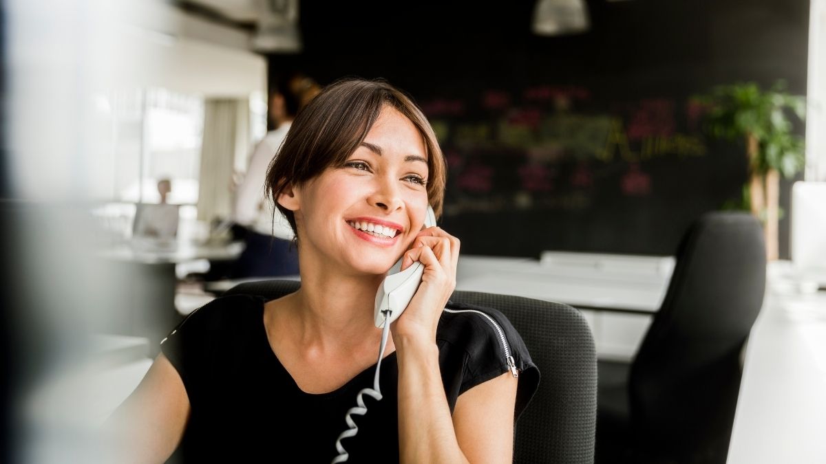 woman with black hair at office using corded phone