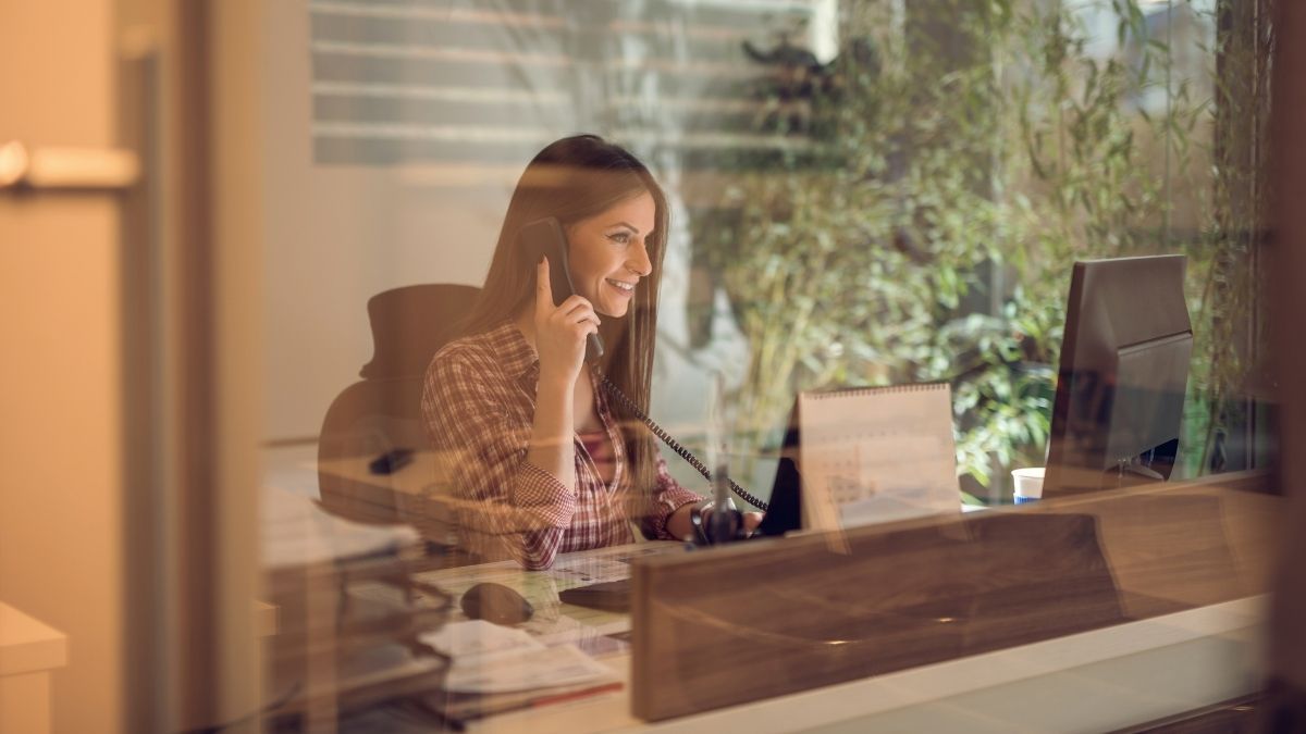 woman in glass office using a laptop