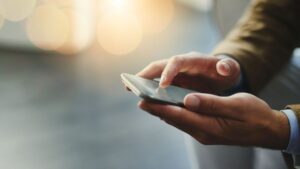 man's hands using mobile